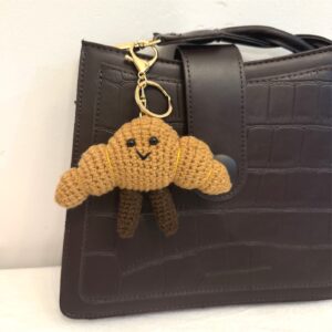 Gehäkelter Croissant-Schlüsselanhänger an brauner Tasche