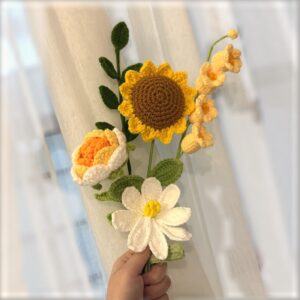 Gehäkelter gelber Blumenstrauß mit Sonnenblume vor weich verschwommenem Hintergrund
