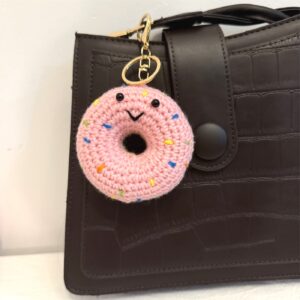 Rosa gehäkelter Donut-Schlüsselanhänger an brauner Tasche
