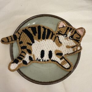 Weiß-brauner Katzen-Untersetzer auf Teller mit gestreiftem Kätzchenmotiv, Pfoten und rosa Ohren
