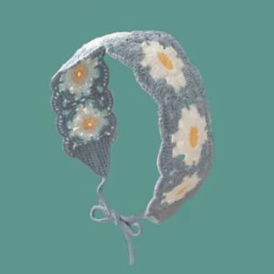 Gebogenes hellblau-weißes Haarband mit floralen Motiven und Bindeband vor türkisfarbenem Hintergrund.