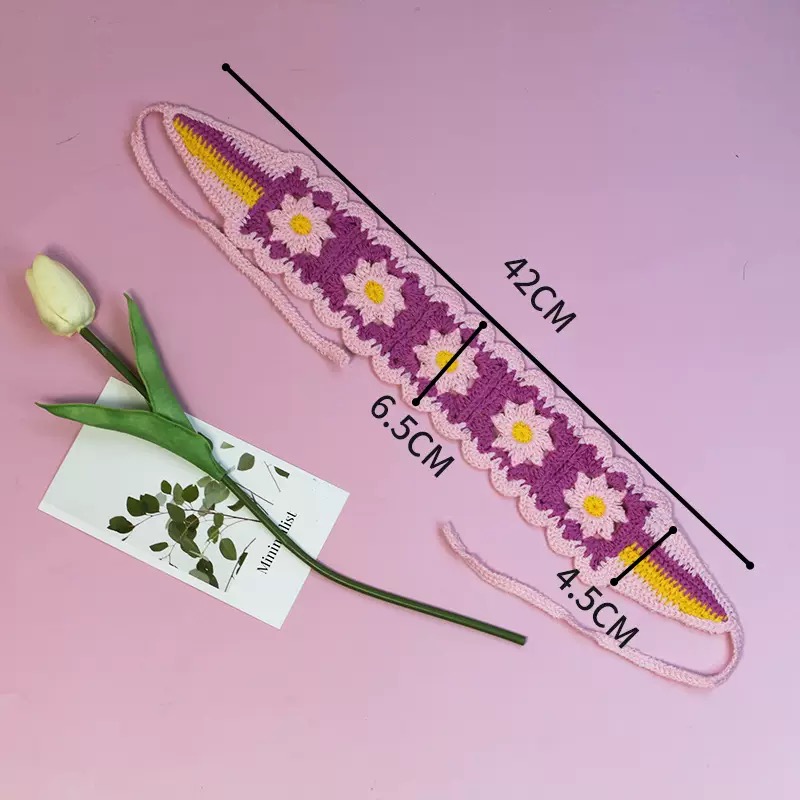 Flach liegendes rosa-violettes Haarband mit Gänseblümchen-Muster und Maßangaben 42 cm, 6,5 cm und 4,5 cm auf rosa Hintergrund.