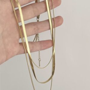 Goldene dreilagige Halskette vor hellem Hintergrund, mit breiter 4-mm-Schlangenkette und zwei feineren Kettenlagen.